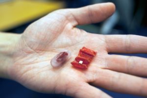 “It’s really exciting to see our small origami robots doing something with potential important applications to healthcare,” Daniela Rus says. Pictured, an example of a capsule and the unfolded origami device. Photo: Melanie Gonick/MIT