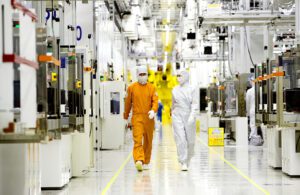 Samsung workers in clean room gear walking down a corridor at a semiconductor fabrication plant