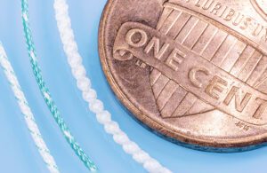 Braided textile material next to a penny coin for scale