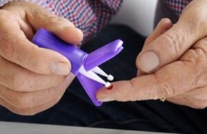 A man uses a Mitra device to stick his finger and collect a drop of blood