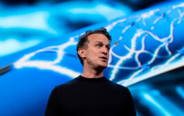 A photo of Synchron co-founder and CEO Dr. Tom Oxley giving a TED Talk with an image of the Stentrode device displayed behind him.