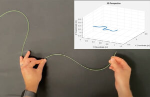 A photo of a fiber optic sensor reporting its 3D location as it's manipulated by a pair of hands.