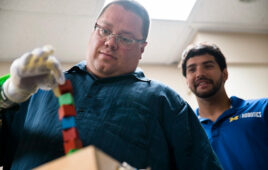 A patient controls a prosthetic arm and hand using Blue Arbor's RESTORE Neuromuscular Interface System as co-founder Alex Vaskov looks on.