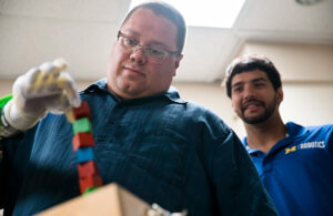 A patient controls a prosthetic hand using Blue Arbor's Restore Neuromuscular Interface System as co-founder Alex Vaskov looks on.