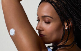 A photo of a woman wearing an Abbott Lingo over-the-counter wearable biosensor for continuous glucose monitoring.
