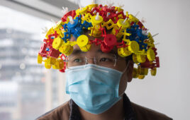 A photo of Boston University researcher Ke Wu wearing a magnetic metamaterial device designed to improve the quality of MRI brain scans.