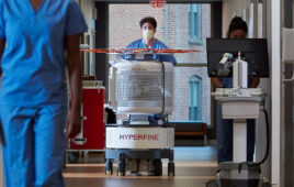 A photo of a Hyperfine Swoop MRI scanner being pushed down the hall of a hospital.