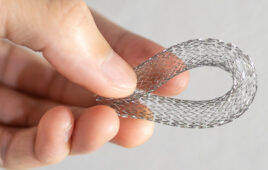 A photo of a hand holding a nitinol tube for a medical device.