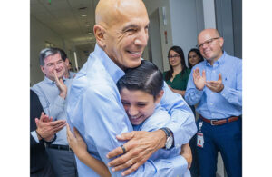 Retired Edwards Lifesciences CEO and Chair Mike Mussallem hugging a child on patient day.