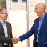 A photo of Edwards Lifesciences CEO Bernard Zovighian (left) and retired CEO and Chair Mike Mussallem shaking hands.
