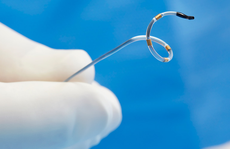 A photo of Medtronic's Symplicity Spyral renal denervation catheter with a gloved hand for scale.