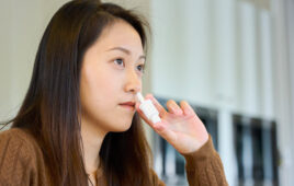 A photo of a woman using a nasal vaccine delivery device.