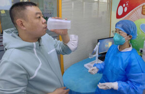 A photo of a patient inhaling an aerosolized Covid-19 vaccine from a disposable cup.