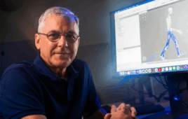 Portrait of Rice University's Benjamin Fregly sitting next to a computer monitor.