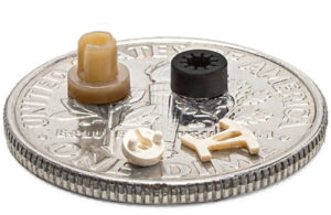 A photo of Micromolded plastic components on a dime for scale