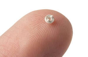 A photo of a tiny micromolded medical device component on a fingertip.