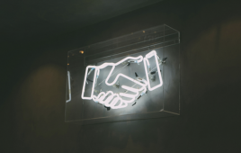This is an Unsplash image of a lighted sign showing a handshake to go along with a story about Philips' chief medical officer discussing medtech partnerships.