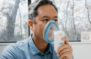 A photo of Vocxi Health CEO Ping Yeh with the MyBreathPrint diagnostic device.