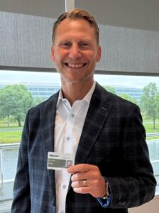 A photo of Baxter President and CEO Andrew Hilder holding a badge.