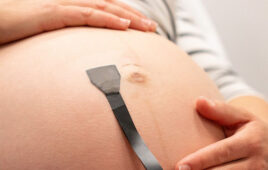 A photo of a soft, wearable ultrasound patch on a pregnant woman.