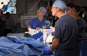 A photo of surgeons watching as a humanoid performs a gallbladder surgery.
